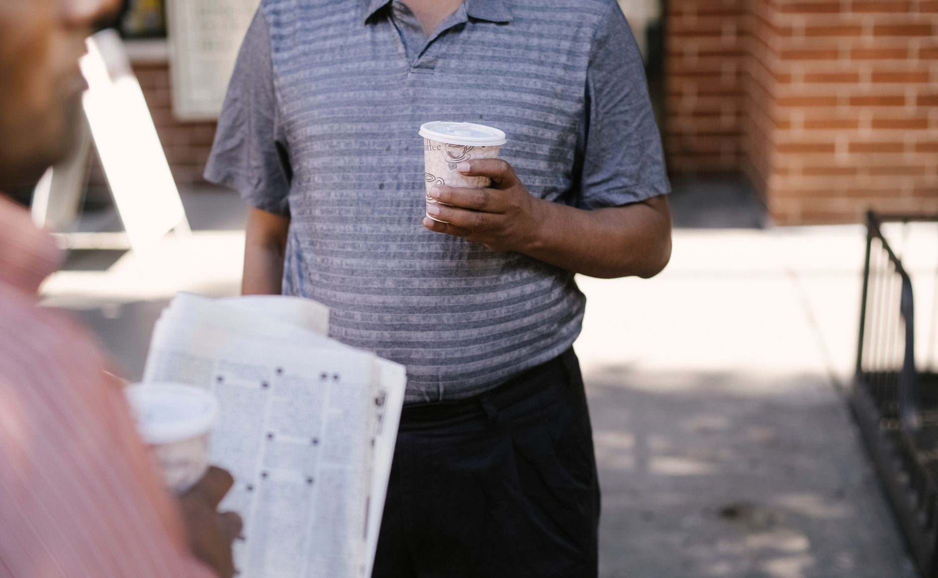 Crop anonymous ethnic male friends with coffee to go and newspaper speaking on city pavement — Die besten Gewinne im Nv Casin