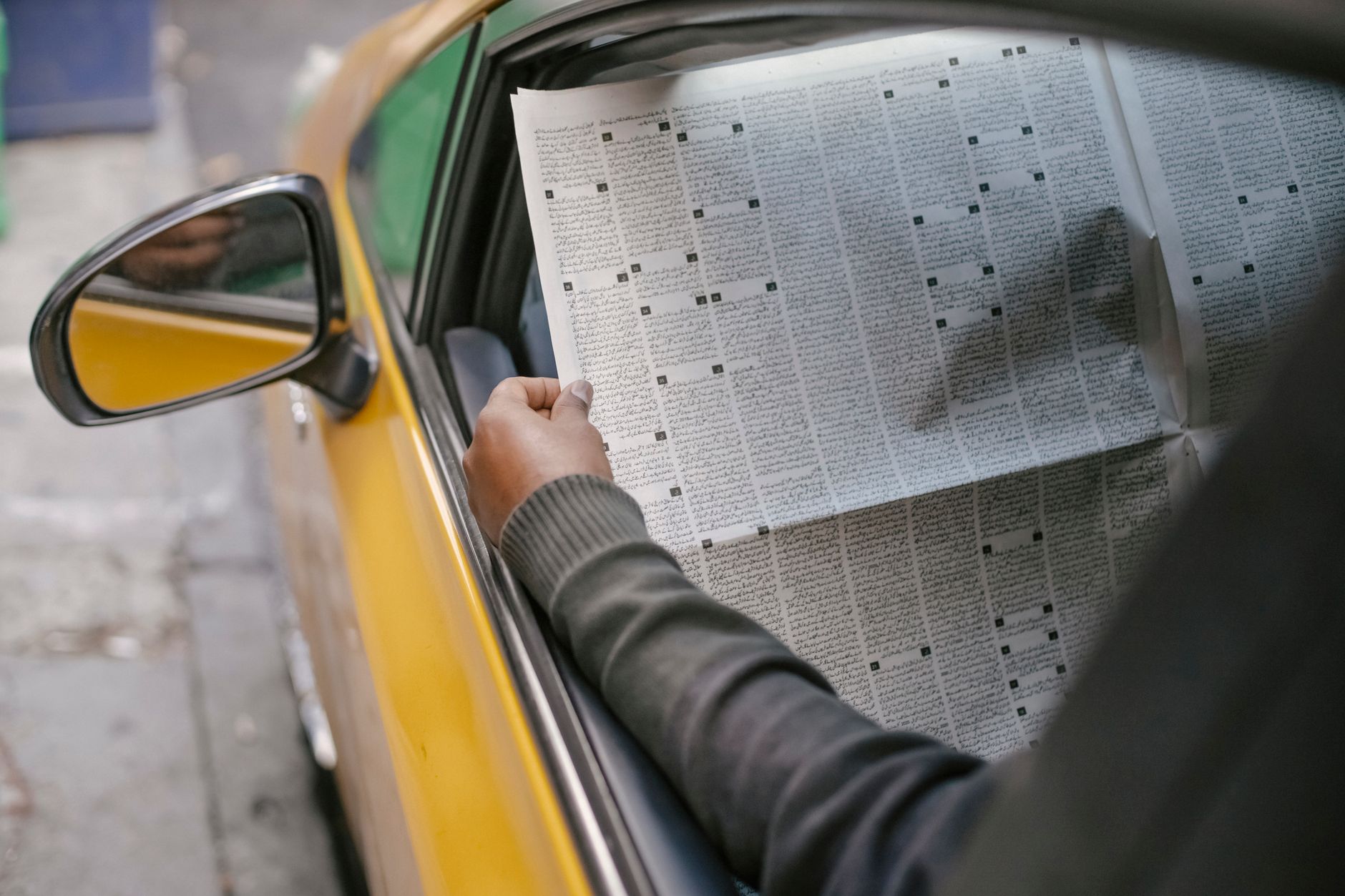 Crop unrecognizable person reading daily newspaper while sitting in car with opened window — Explorer la plateforme Fatpirate