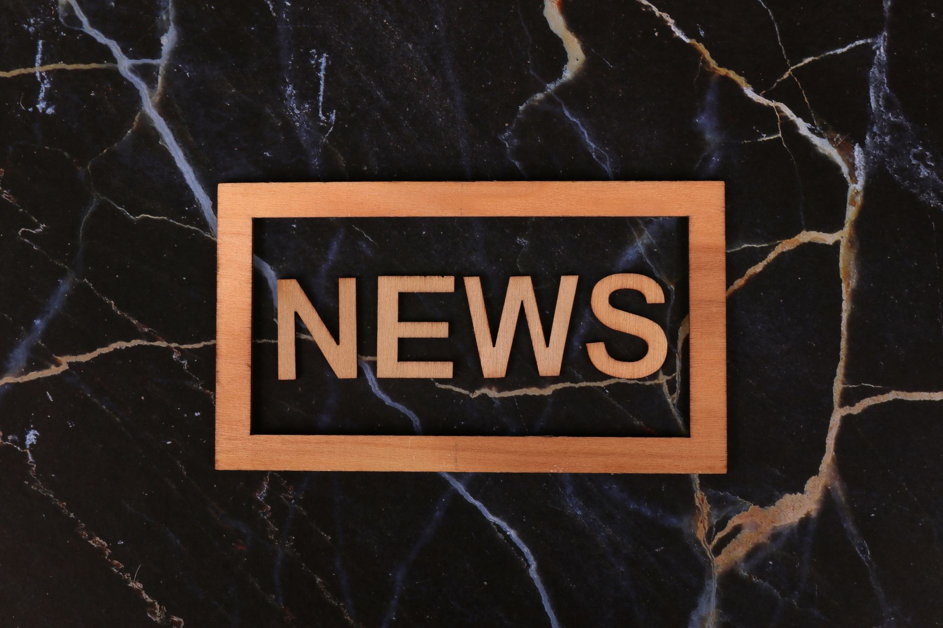 Wooden text of 'news' outlined on a dark, marbled surface, creating a striking contrast. — Fatpirate Casino un regard complet