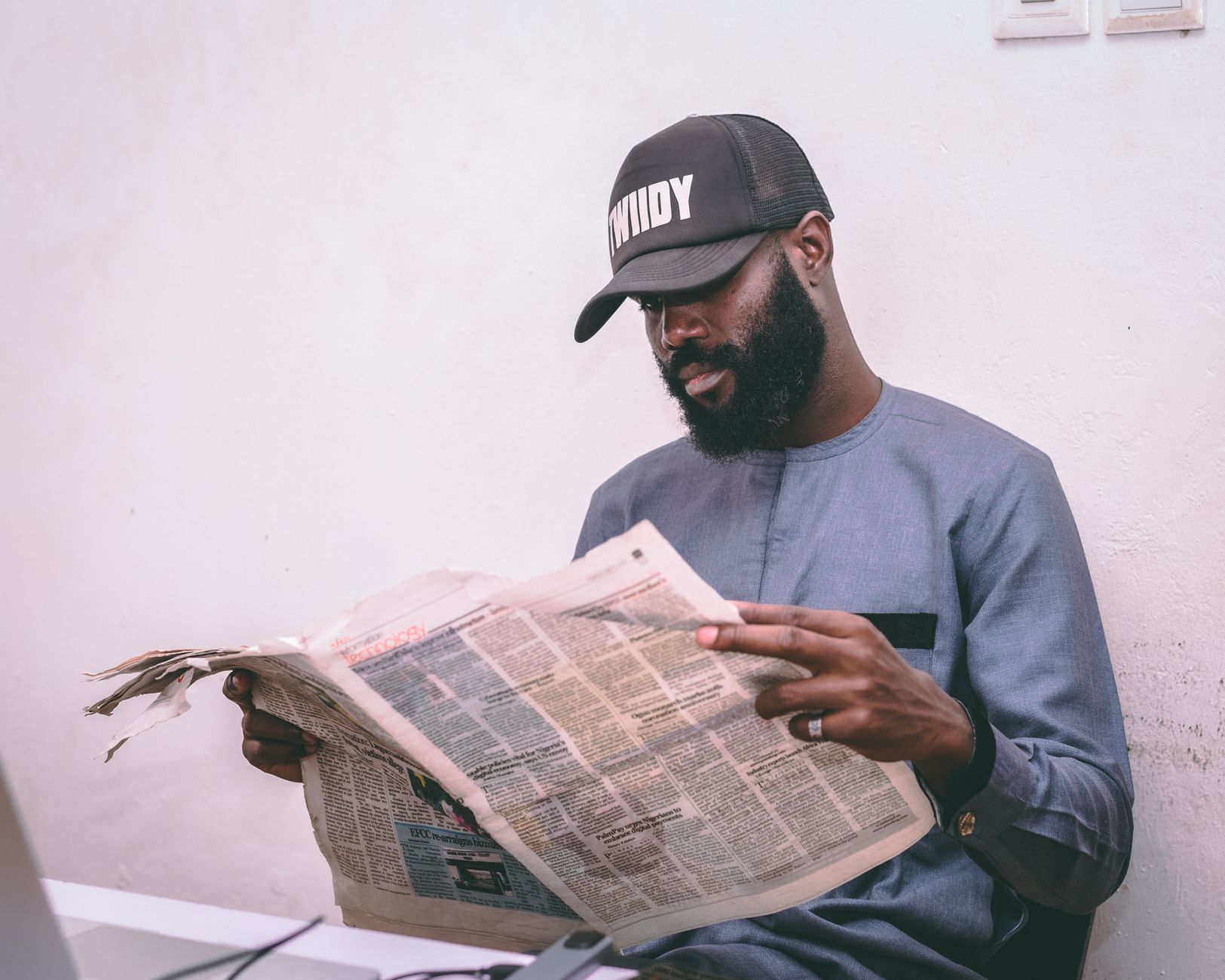 Adult man reading a newspaper indoors, wearing a cap and traditional attire. — Sensible Medical insurance Preparations