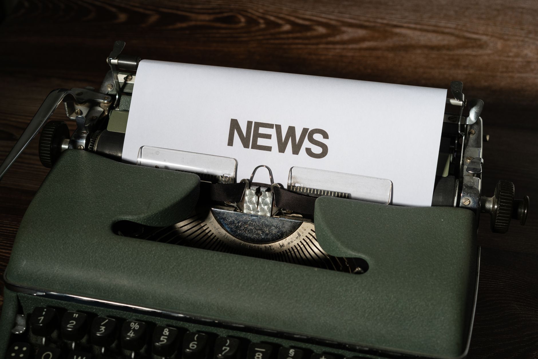 A retro typewriter featuring a 'NEWS' headline typed on white paper against a wooden surface. — Wie man im Immerion Casino ri