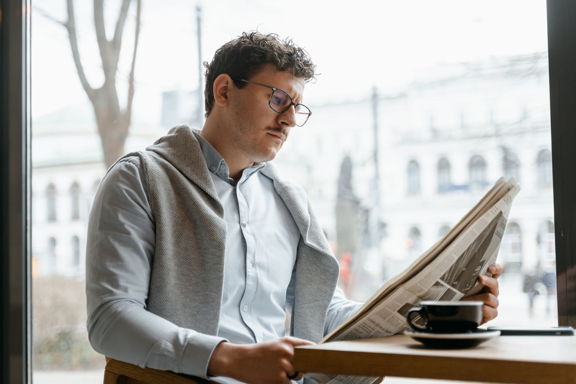 Adult man reads a newspaper by a café window, enjoying a coffee break indoors. — Wie steht HashLucky Casino im Trend der Onli